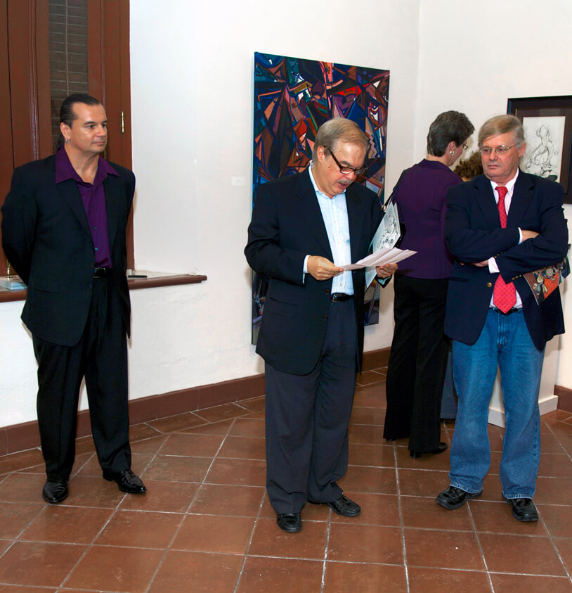 Photo of the Museo de las Américas Reception in Old San Juan, Puerto Rico at the venue of artist and painter Michael J. Korber with Gallery owner and representative - Jose Alegría and Art Historian and art critic - Manuel Alvarez Lezama addressing the opening at Korber's Art Retrospective Exhibit, titled - A decade of line and color, in 2007.