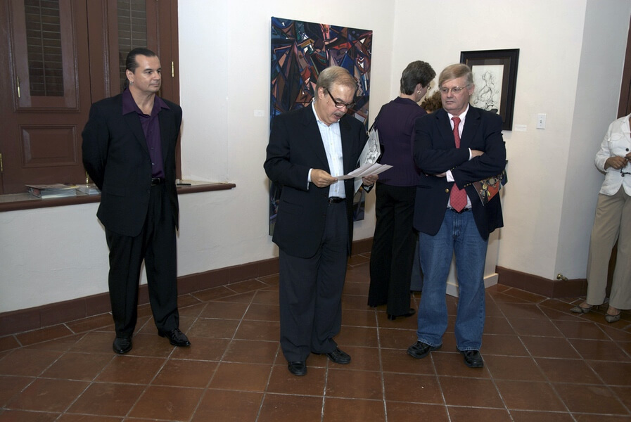 Photo of the Museo de las Américas Reception in Old San Juan, Puerto Rico at the venue of artist and painter Michael J. Korber with Gallery owner and representative - Jose Alegría and Art Historian and art critic - Manuel Alvarez Lezama addressing the opening at Korber's Art Retrospective Exhibit, titled - A decade of line and color, in 2007.